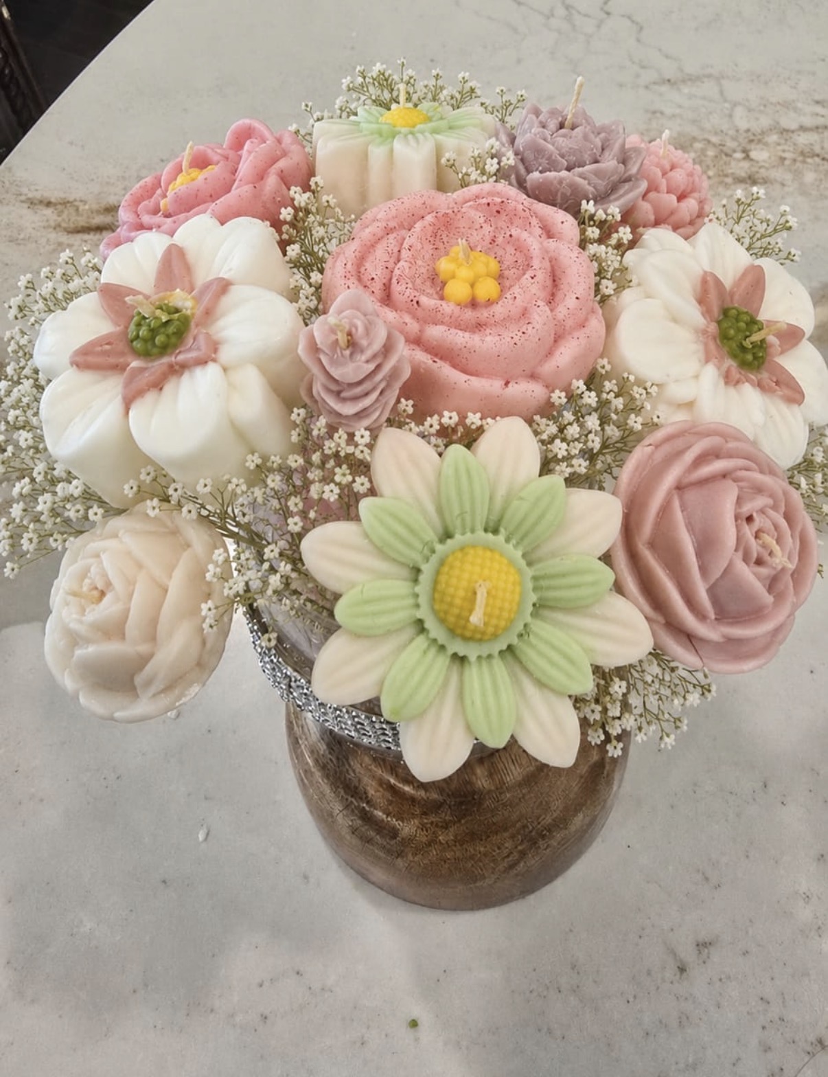 Bouquet of pastel rose and daisy floral forms with white filler flowers in a wood-look vase
