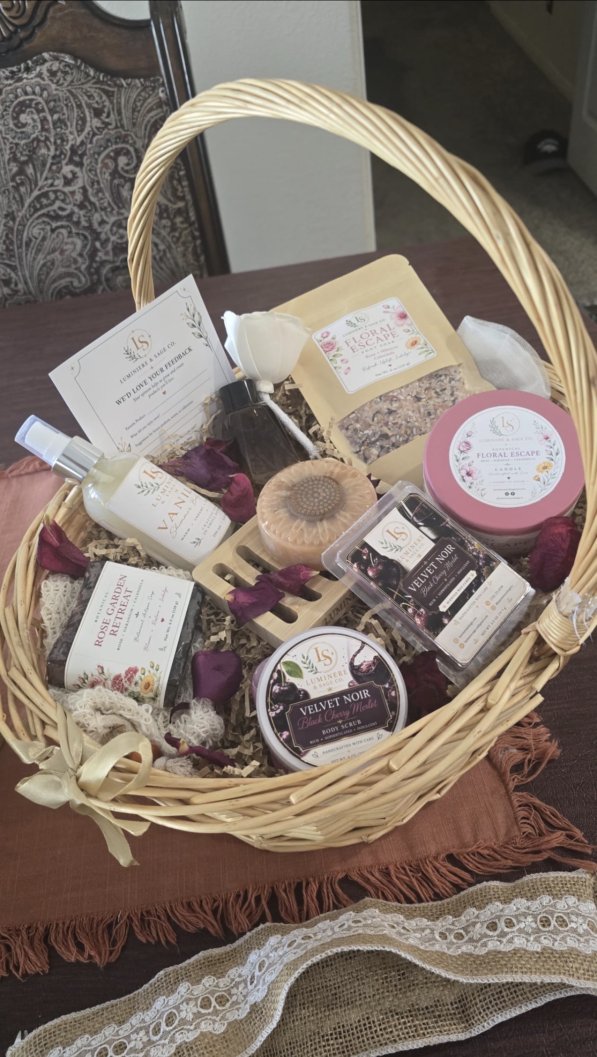 Wicker gift basket with branded soap, candle tin, bottles, a pouch and other Luminere & Sage products