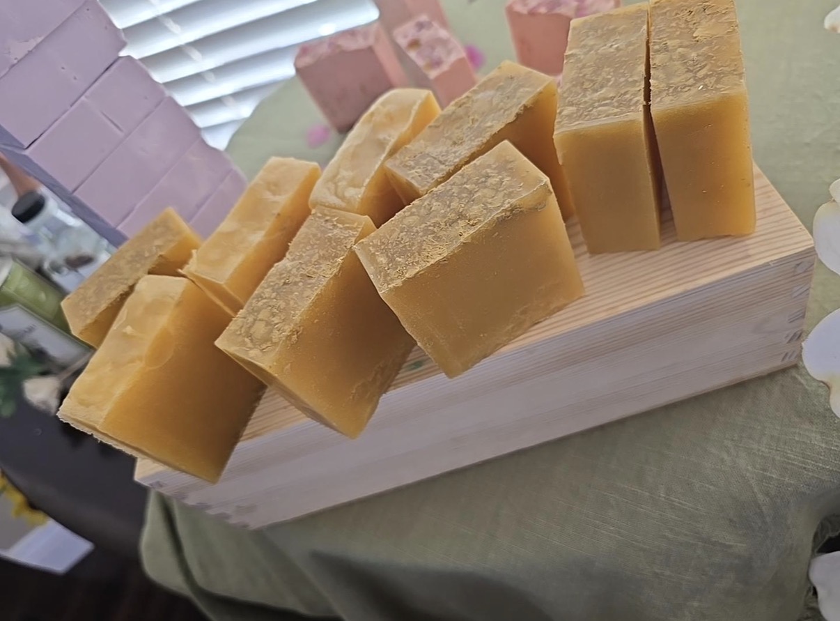Golden tan square soap bars on a wooden block with pastel bars behind