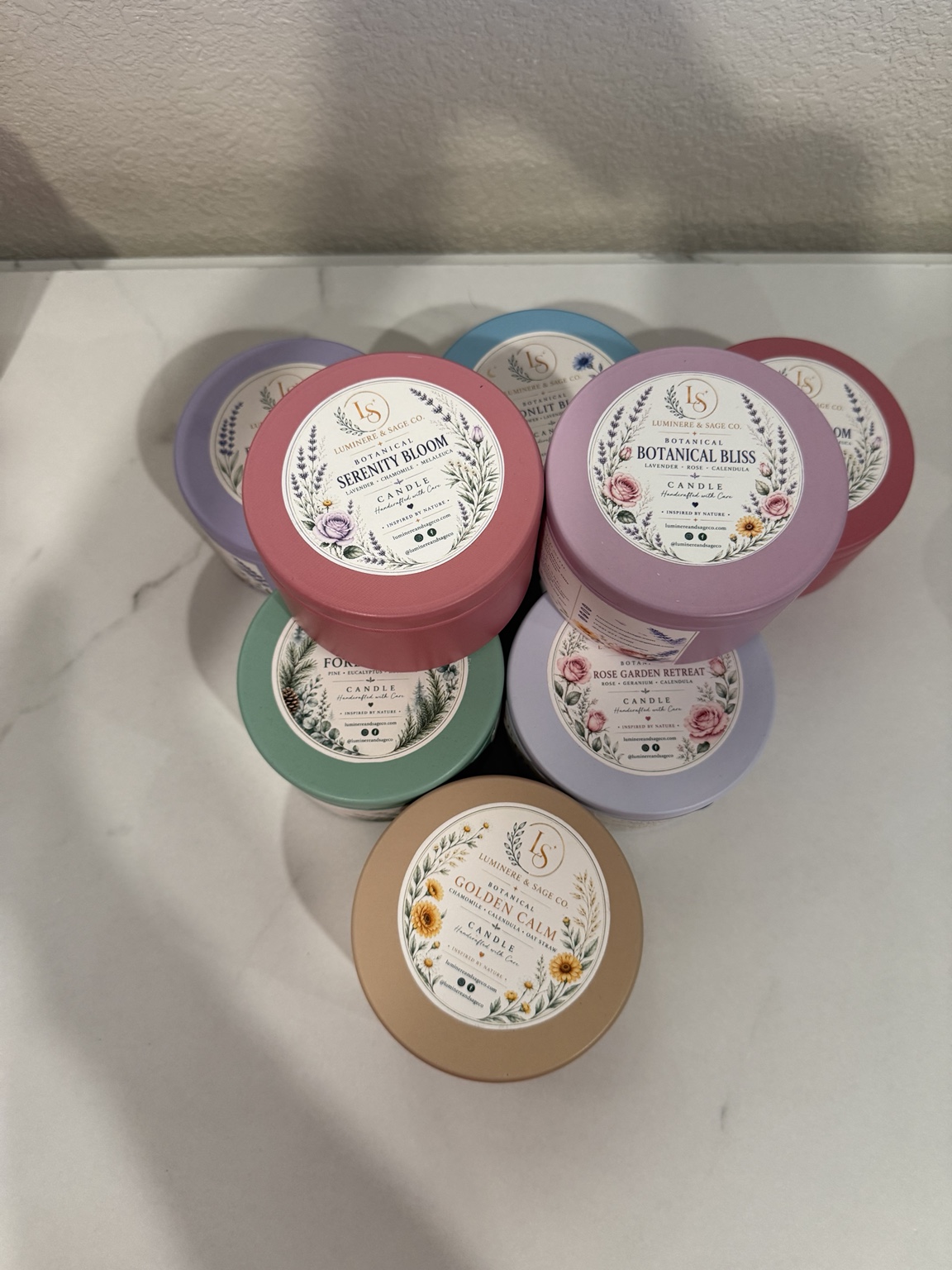 Pastel Luminere & Sage botanical candle tins arranged together