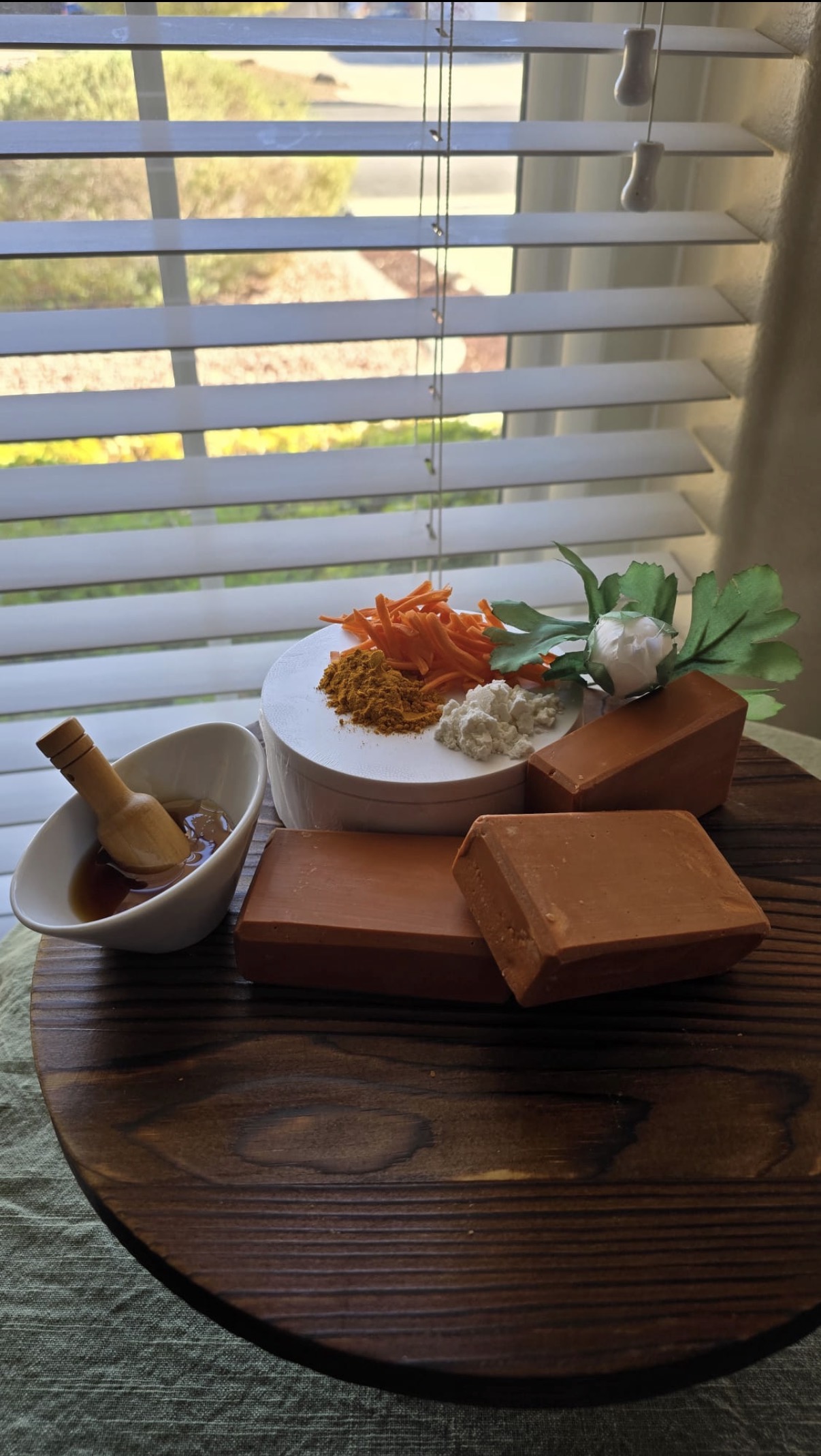 Orange-brown rectangular soap bars on a wood table with a small bowl and botanical decorations