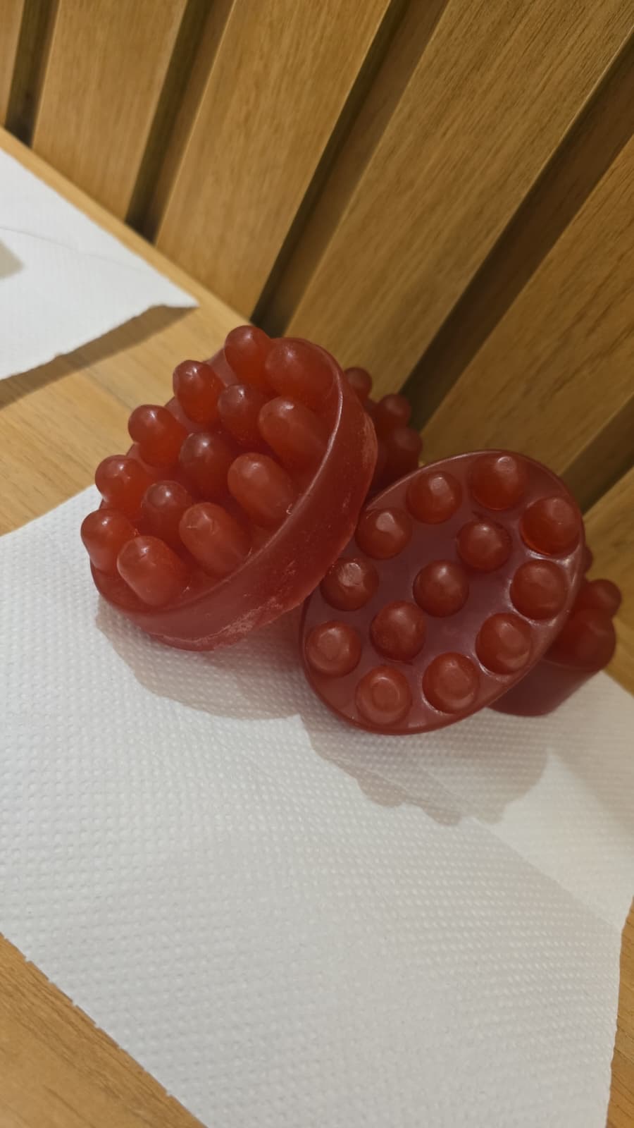 Red massage-shaped facial soaps on a white towel against a wooden background